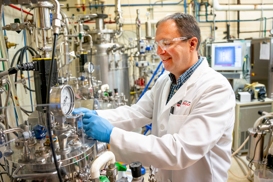 photo of man in lab with tubes, gauges, equipment, monitor