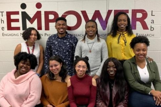 photo of nine people with wall sign