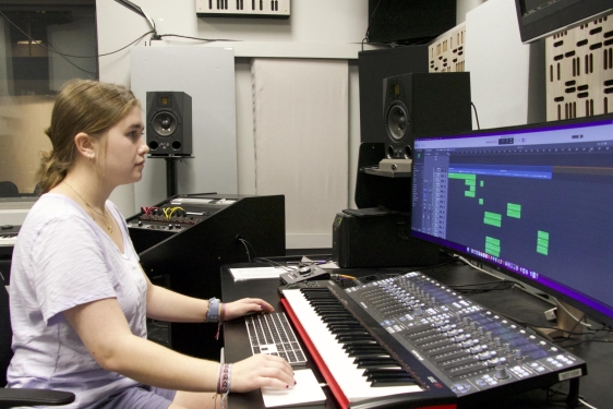photo of student sitting at sound board with computer screen