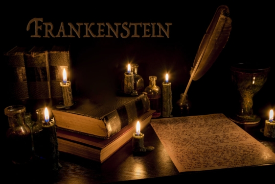 graphic with Frankenstein word, quill pen and paper, candles
