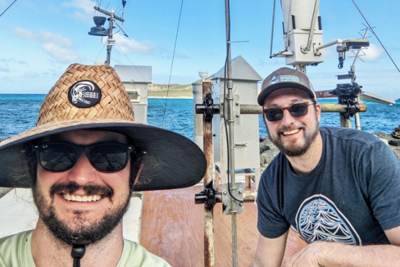 photo of two men, with instruments and sea in background