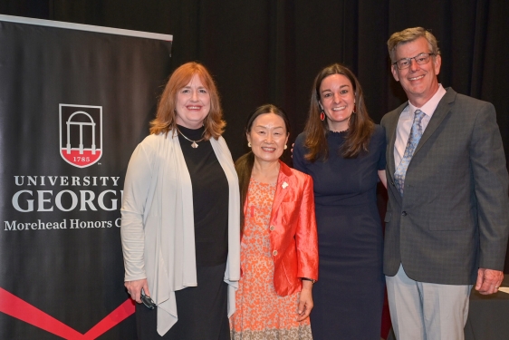 photo of four people, with banner