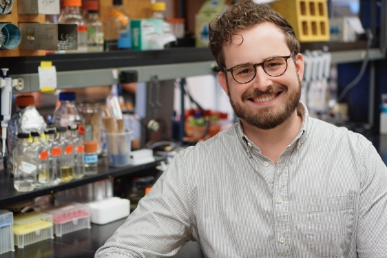 photo of man in laboratory, shelves and containers in background