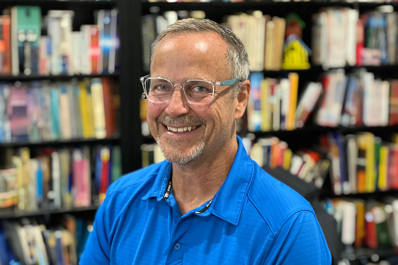 photo of man, bookshelves and books in background