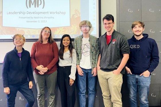 group photo of six people, with projection screen in background