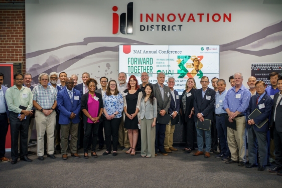 group photo of 31 people, indoors, sign in background