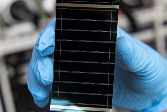 photo of tiny solar cell, held by blue-gloved hand
