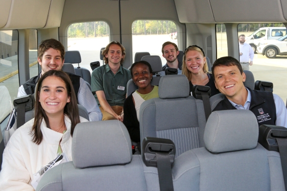 photo off seven smiling students inside a van