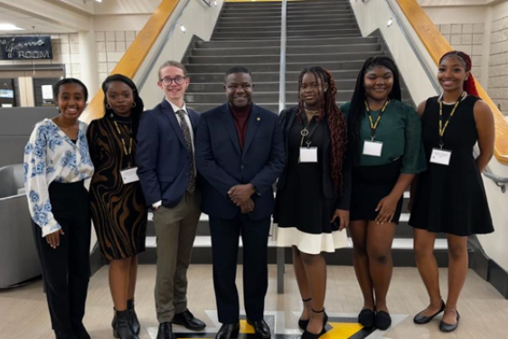 photo of seven people, staircase in background