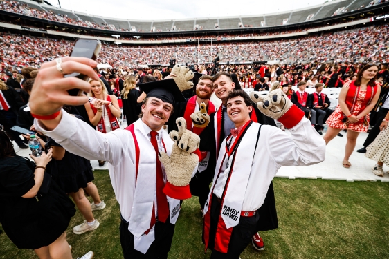 photo of people taking selfies in stadium, crowd in background