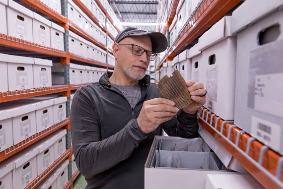 photo of man in aisle of shelves with boxes