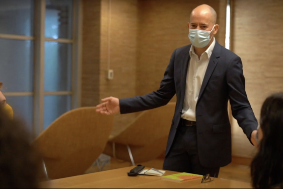 photo of man with mask standing at table, arms spread