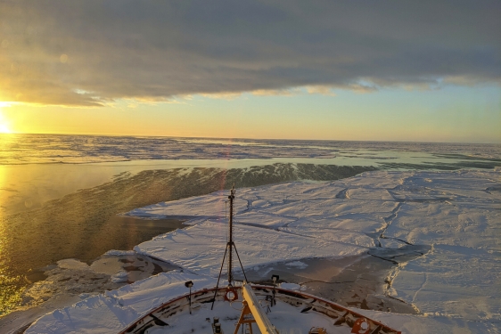 photo of sunrise over frozen sea, with bow of ship