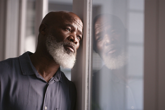 photo of man leaning against window 