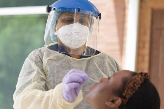 photo of masked nurse administering nasal swab test to patient