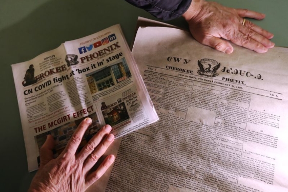 photo of hands and two newspapers in different languages