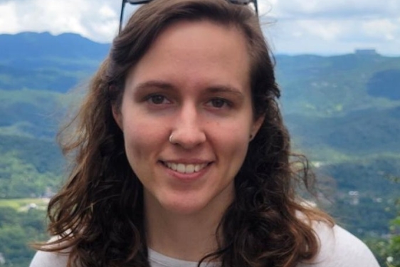 headshot photo of woman, outdoors, mountains in background