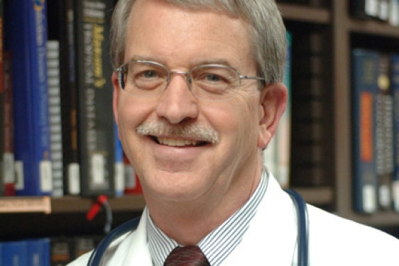headshot of man, with books in background
