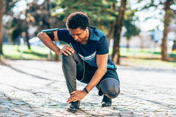 photo of runner kneeling to touch ankle