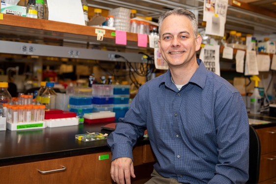 photo of man in lab, with table and lab equipment