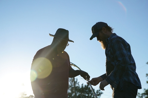 photo of two men, with stalk, sun, and sky