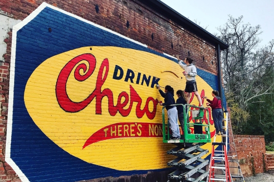 photo of students with lift, painting mural