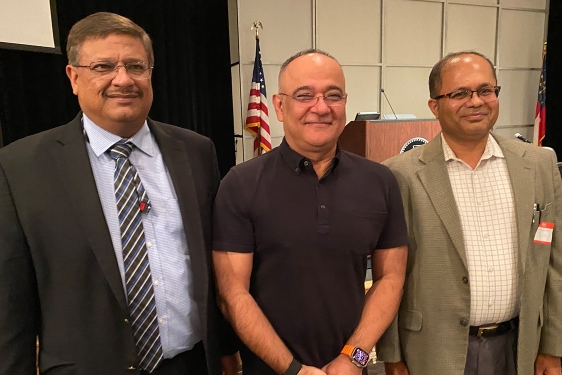 photo of three men, flag and podium in background